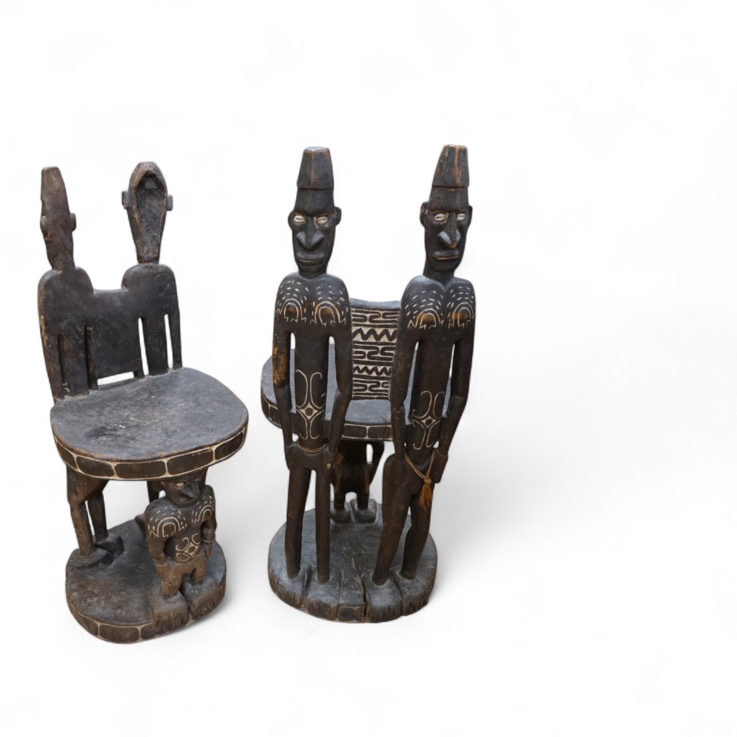Papua New Guinea Sepik River, a near pair of ‘ceremonial’ figural chairs, each carved from a single section of a tree trunk with integral male and female backs and an castor figure front support with cowrie shell eyes. H